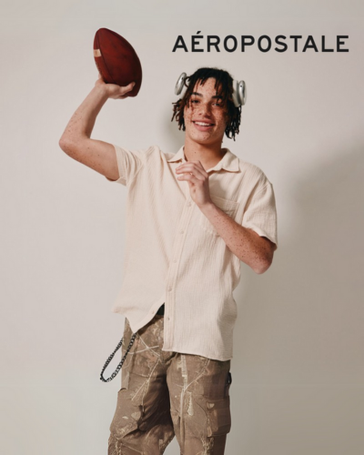 Guy with headphones and beige shirt tossing football