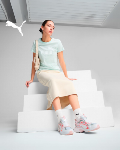 female model sitting on white stairs in t-shirt and long skirt with tennis shoes