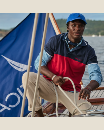 male model in red and blue polo with khakis sailing