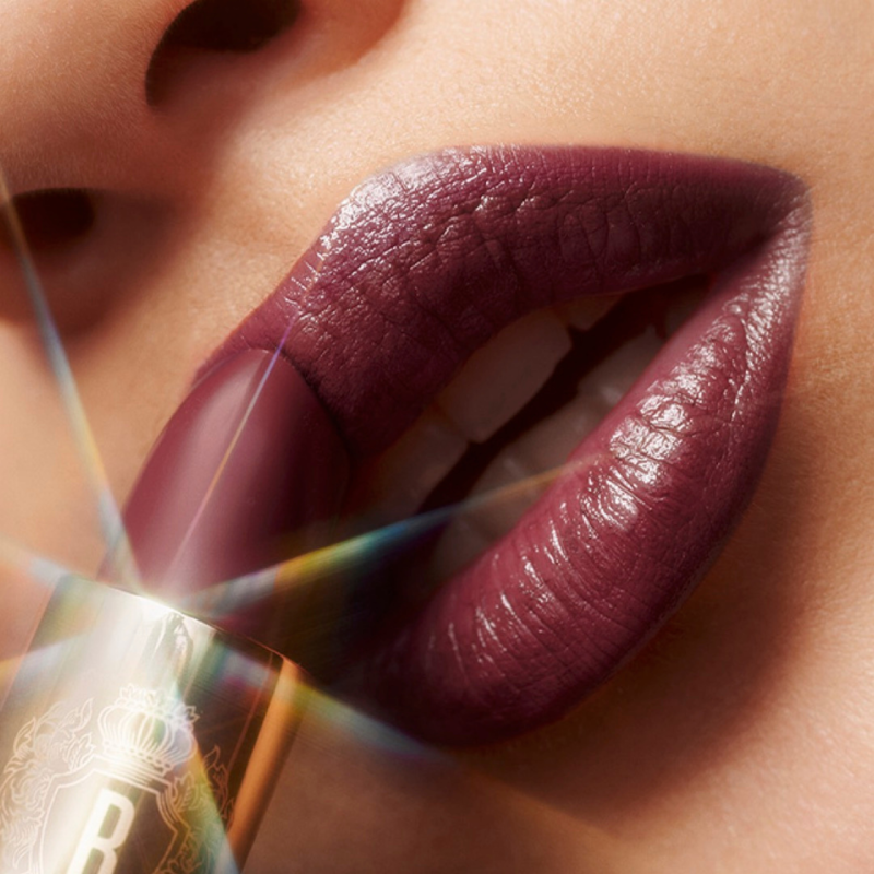 closeup of lips applying wine colored lipstick
