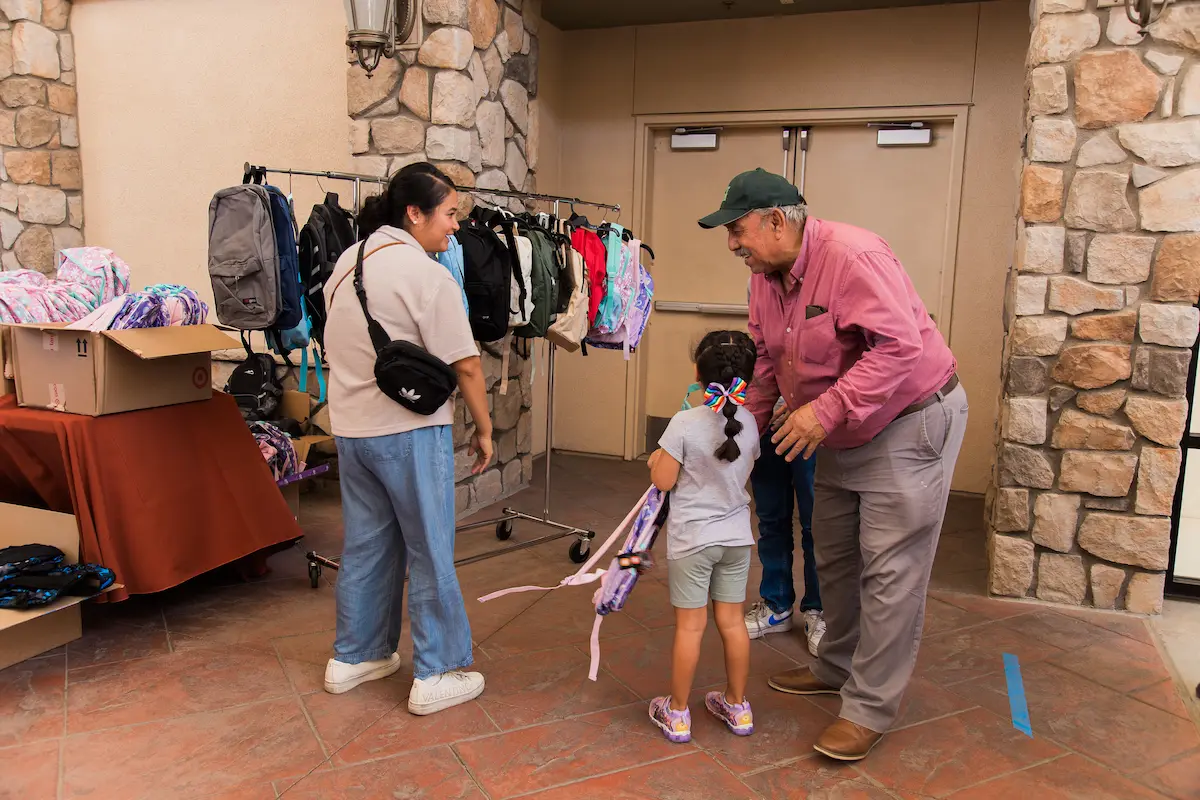 Parent with child choosing new free backpack