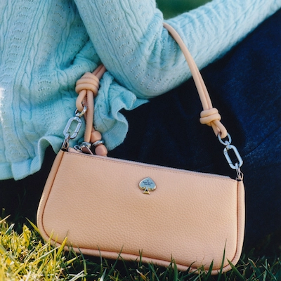 Woman sitting on grass with Kate Spade handbag