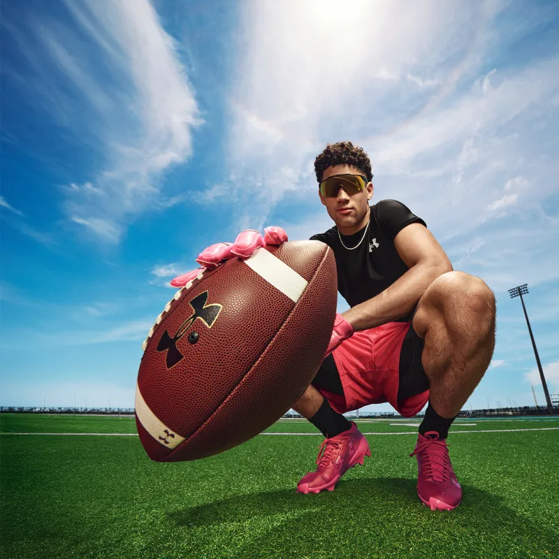 Man holding football wearing Under Armour gear