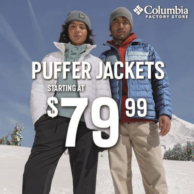 Two people in puffer jackets and beanies standing in the snow