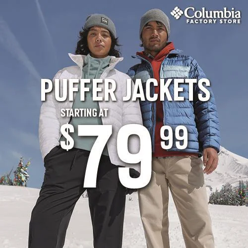 Two people in puffer jackets and beanies standing in the snow